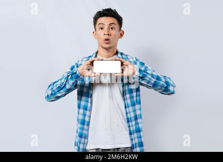 Amazed young man showing ad on cellphone. Surprised handsome man showing the horizontal screen of his cell phone, Surprised guy in glasses showing Stock Photo
