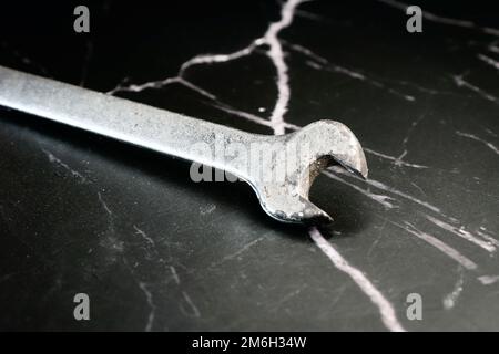 old rusty fixed wrench for nuts on a dark marble background Stock Photo