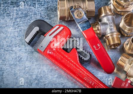 Brass pipe connectors monkey wrench gate valve on metallic background plumbing concept. Stock Photo