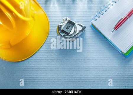 Checked notebook pen building helmet measuring tape. Stock Photo