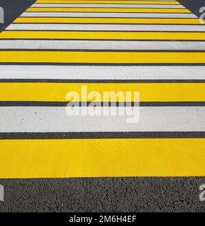 Freshly painted pedestrian crossing with yellow and white markings on asphalt, vertical photo, sunlight Stock Photo