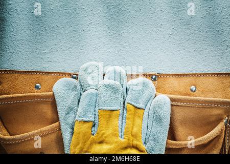 Leather tool belt safety gloves on concrete background. Stock Photo