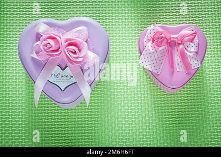 Metal pink heart-shaped present boxes on green background celebrations concept. Stock Photo