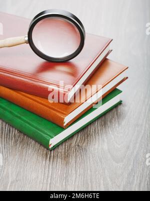 notebooks and magnifier on wooden background Stock Photo