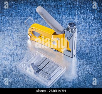 Stapler gun metal staples on metallic background. Stock Photo