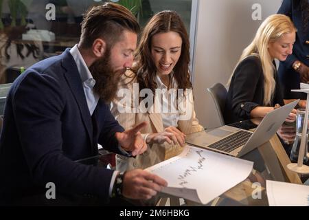 Group of young creatives who discuss graphics during a brainstorming for an innovative start-up. Concept of innovation and start of business Stock Photo