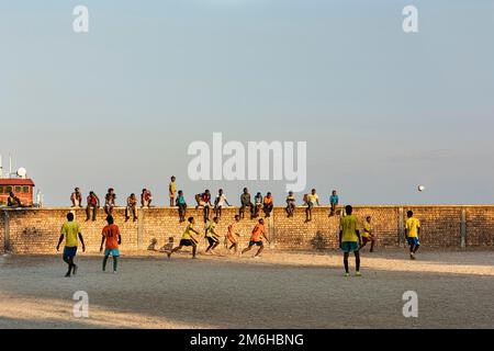 Boys, football pitch, youths playing football, wall with spectators, Mahajanga, Madagascar Stock Photo