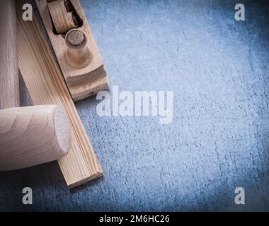 Wooden shaving plane hammer stud on scratched metallic background copyspace. Stock Photo