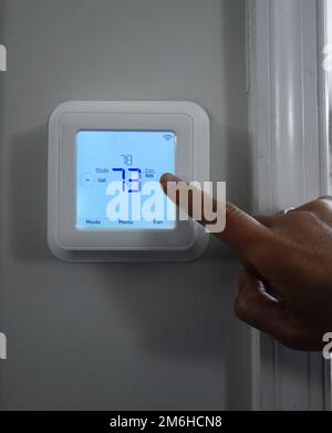 Person adjusting the home temperature on a smart thermostat Stock Photo