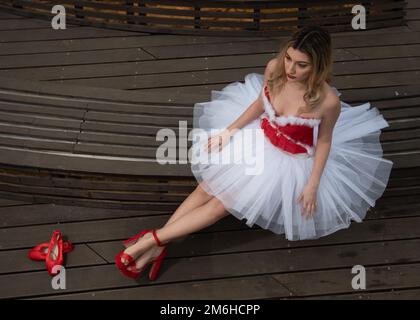 Ballerina wearing christmas white red dress posing on the floor Stock Photo