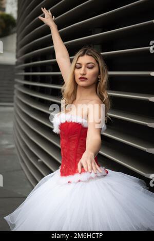 Ballerina wearing white and red christmas ballet dress dancing outdoors Stock Photo