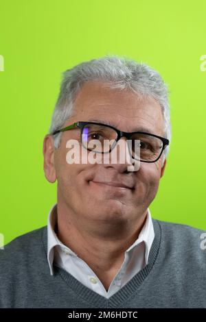 Portrait of handsome caucasian senior man with glasses looking at camera smiling with isolated in green background. Confident businessman ceo boss fre Stock Photo