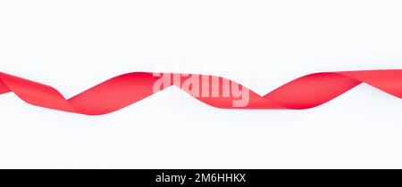 Red gift wrap satin ribbon, isolated on white background. Background with twisted ribbon on white background. Stock Photo