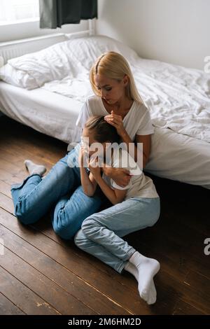 Vertical portrait of loving young mother comforting offended sad little child daughter, showing love and care, expressing support, hugging and Stock Photo