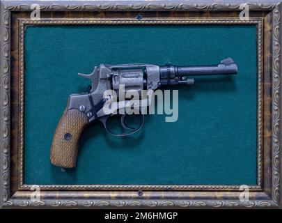 Old revolver revolver in a frame on a turquoise background. Museum retro exhibit Stock Photo