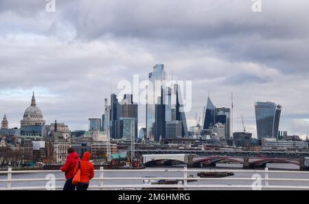 London, UK. 2nd January 2023. People walk along Waterloo Bridge past the City of London skyline. Stock Photo