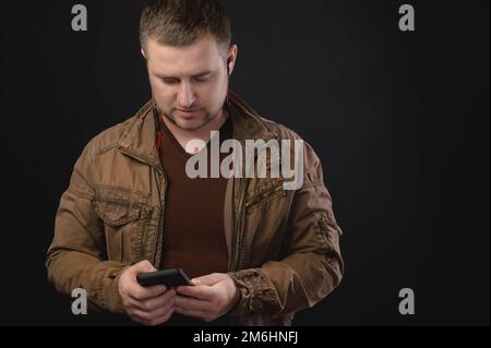 Middle aged Caucasian man uses telephone while standing in studio. Portrait of a freelancer surfing the internet Stock Photo