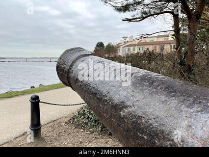 Old cannon pointed at a boat in the sea Stock Photo