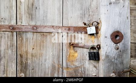 Old vintage metal padlock on a closed wooden door of an old farmhouse. The true style of the village. close-up. focus on the cas Stock Photo