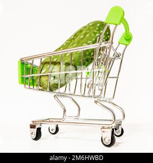 A miniature supermarket cart with a fake green cucumber in it. Stock Photo