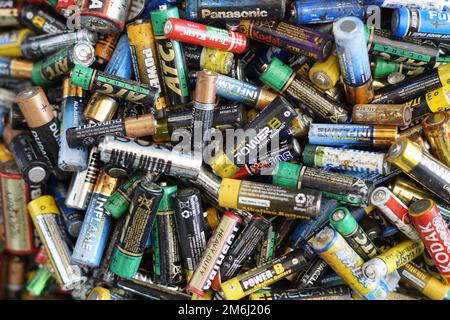 Used batteries from different manufacturers. Waste, collection and recycling. High danger for the environment. Batteries background. AA batteries. Stock Photo