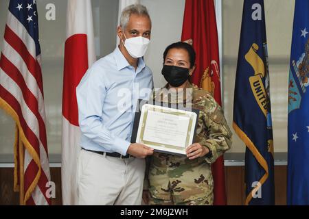 Rahm Emanuel, the U.S. ambassador to Japan, awards U.S. Air Force Capt. Geryn Paguio, an aeromedical crew director with 18th Aeromedical Evacuation Squadron, 18th Wing, during a recognition luncheon on Camp Foster, Okinawa, Japan, April 28, 2022. Paguio received a challenge coin for responding to an overhead call for medical assistance and providing aid to a Japanese passenger during a flight from Okinawa to Tokyo on Sept. 10, 2021. Stock Photo