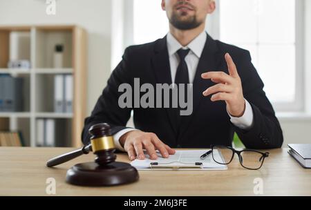 Lawyer providing professional legal consultation while sitting at office desk with gavel Stock Photo