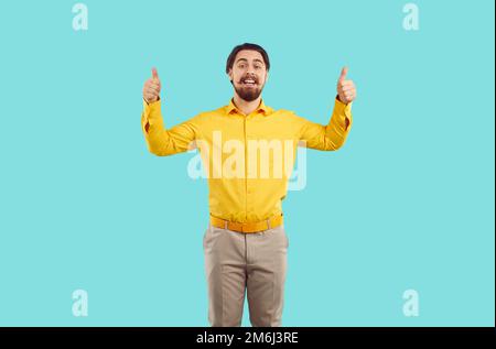 Happy Caucasian man with beard and mustache showing thumbs up standing in turquoise studio Stock Photo