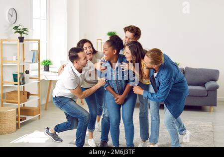 Happy young people laughing at a funny joke their friend has told at a party at home Stock Photo