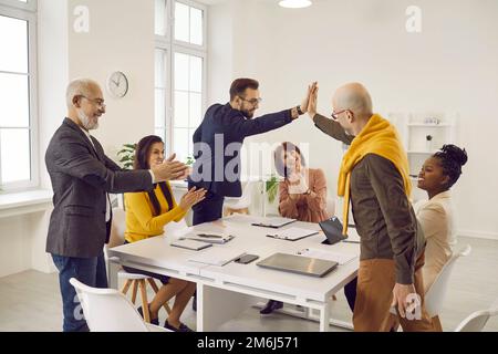 Two happy and satisfied male colleagues give each other high five during business meeting. Stock Photo