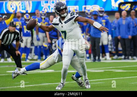 Seattle Seahawks quarterback Geno Smith (7) avoids a tackle while throwing a pass against the Los Angeles Rams during a NFL football game, Sunday, Dec Stock Photo