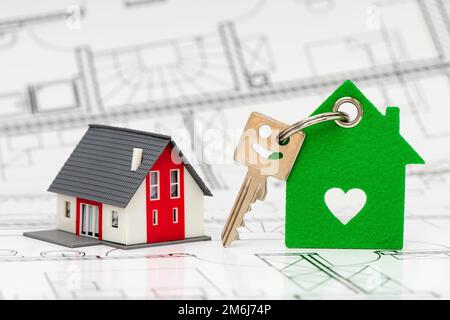 Model home with key standing on construction plan Stock Photo