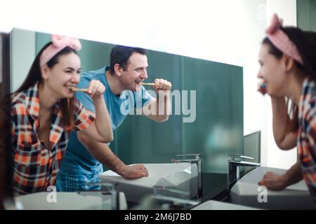 Happy Young brunette Couple Brushing Teeth In Bathroom, Loving Man and His Wife Stock Photo