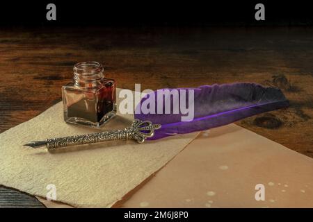Feather quill pen with a vintage ink well and old paper Stock Photo