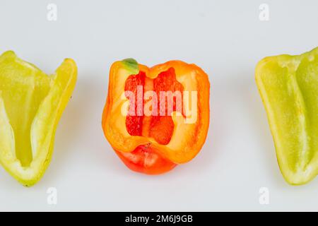 Halved green and red bell peppers isolated on white background. Cutting contour. View from above Stock Photo