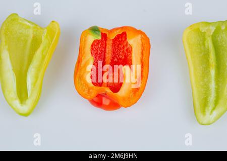 Halved green and red bell peppers isolated on white background. Cutting contour. View from above Stock Photo