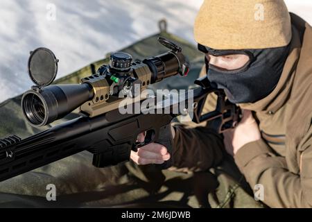 A sniper rifles with an optical sight in  hands man aiming lying down winter day Stock Photo