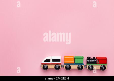 Train children toy, preschool kids game. Locomotive and carriages, wooden colorful blocks construction on pink color background Stock Photo