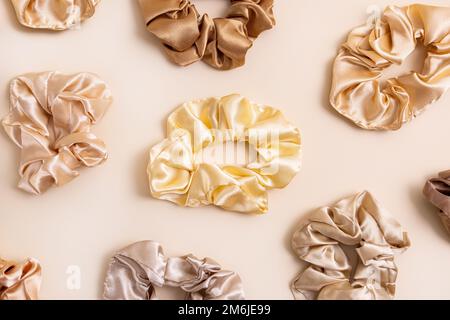 Collection of trendy silk elastic bands scrunchies on beige background. Diy accessories and hairstyles concept, luxury color Stock Photo