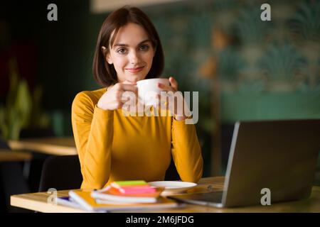 Attractive young woman entrepreneur working at cafe, drinking coffee Stock Photo