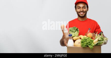 Delivery Concept - Handsome African American delivery man carrying package box of grocery food and drink from store. Isolated on Stock Photo