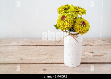 A bunch of lime green zinnias in a pottery vase. Stock Photo