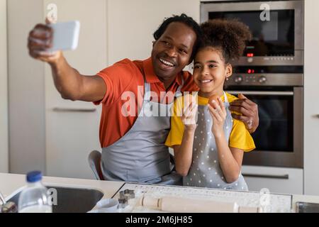 Family Fun. Black Father And Daughter Taking Selfie On Smartphone In Kitchen Stock Photo