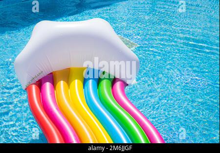 Inflatable mattress, rainbow colors. swimming in the pool on a sunny day. Stock Photo