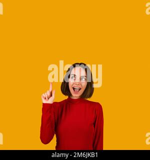 Happy millennial woman pointing upwards showing eureka gesture Stock Photo