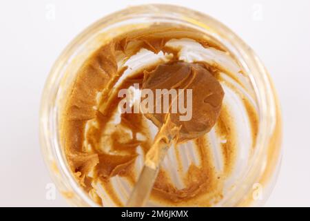 Peanut butter in an open jar. Empty peanut butter container. The last spoonful of delicious pasta snacks Stock Photo