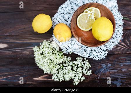 Still life of fresh lemons and elderberry flowers. Ingredients for lemonade and juice from syrup from elderberry flowers. Seasonal summer food. Healin Stock Photo