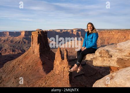 Portrait of cheerful woman sitting on rock in desert Stock Photo