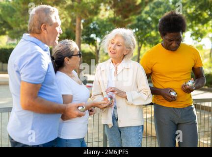 Two adult couples share their impressions after playing petanque Stock Photo