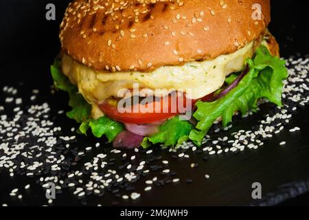 Close-up view on cheeseburger and seasam on a plate. On a black background Stock Photo